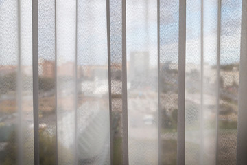 Transparent white curtain on window and city behind it. Curtain background