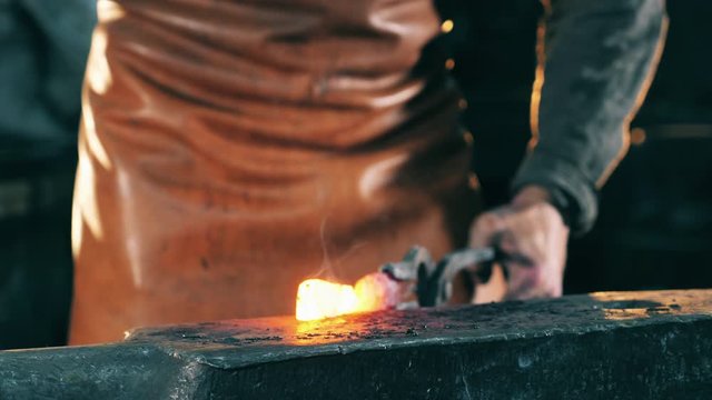 Professional blacksmith shaping knife on anvil.