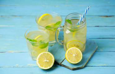 Lemonade or mojito cocktail with lemon and mint on wood background