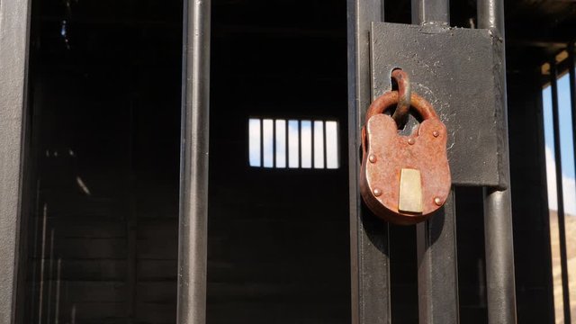 Old fashion lock on a metal bars used to imprison criminals.