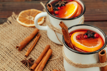 Close up of mulled wine cup with spices and berries on grey table