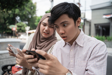 asian college student enjoy the game using smartphone when sitting together in the park