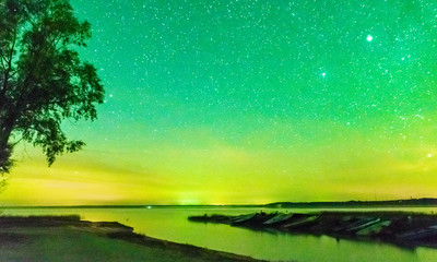 Fototapeta na wymiar picture with a northern lights on the lake, blurred background. fuzzy and moving human silhouettes in the foreground