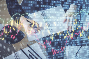 Forex chart hologram on hand taking notes background. Concept of analysis. Multi exposure