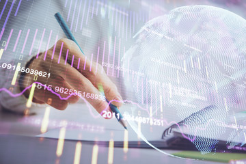 Financial forex graph displayed on hands taking notes background. Concept of research. Double exposure