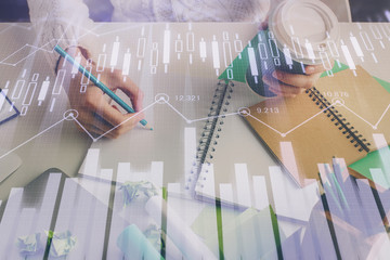 Financial forex graph displayed on hands taking notes background. Concept of research. Multi exposure
