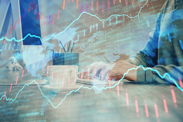 Multi exposure of graph with man typing on computer in office on background. Concept of hard work.