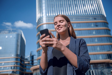 happy young woman with smartphone on modern building background
