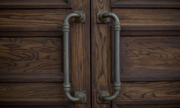 handles on a brown wooden door made of metal