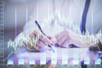 Double exposure of hands making notes with forex chart huds. Stock market concept.
