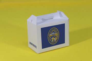 Nebraska flag on white box with barcode and the color of state flag on yellow background. The concept of export trading from Nebraska, paper packaging for put products.