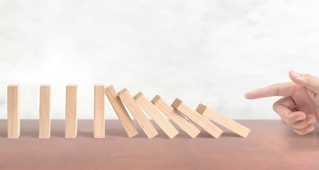 Hand stopping the Domino effect stopped by unique