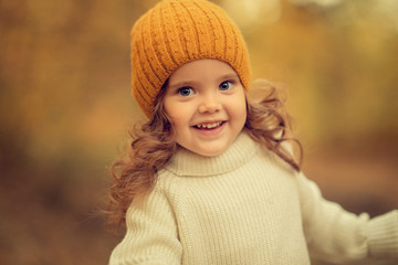 cute girl with curly hair in beanie looking at the camera outdoors