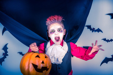Halloween kids: little boy in a costume of vampire Dracula scares on pumpkin patch