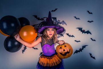 Little girl in a costume of witch with witch hat celebrates Helloween
