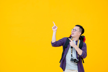 Young smiling Asian  male backpacker looking up while pointing to copy space