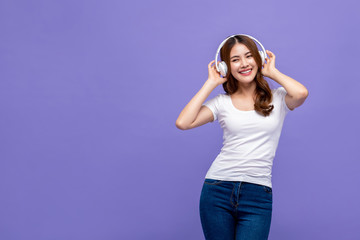 Obraz na płótnie Canvas Happy young pretty Asian woman listening to music beside copy space
