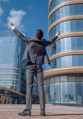 rear view. happy businessman standing in front of tall office building.