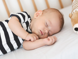 Sleeping newborn baby lying on his side in crib, closeup