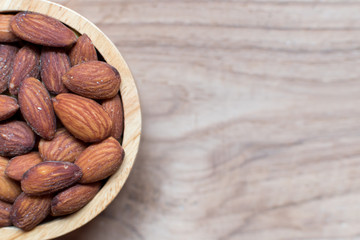 Selective focus ,Almonds roasted salt in the wood bowl on wooden table background and copy space for design text or word. Concept :Wallpaper healthy food magazine or diary.