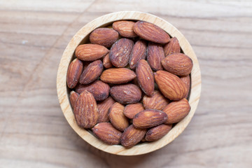Almonds roasted salt in the wood bowl on wooden table background and copy space for design text or word. Concept :Wallpaper food magazine or diary.