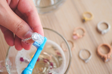 Jeweller hand cleaning and polishing vintage jewelry diamond ring closeup