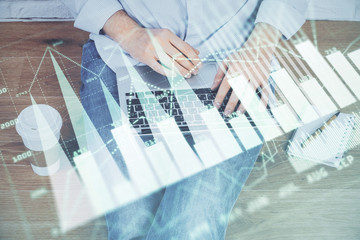 Double exposure of businessman's hands with laptop and stock market graph background. Concept of...