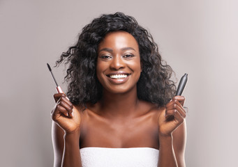 Beautiful african american woman holding opened mascara in her hands