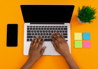 Female using laptop and smartphone with black screen at workplace