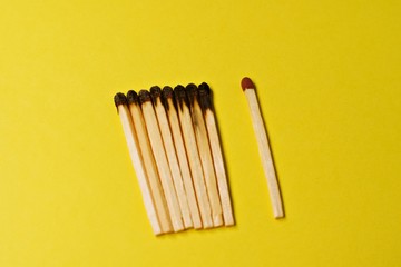 Symbol of danger with matches on yellow  background top view , pile of match arrange in a row with one  unBurnt match , unlit matches , unique and various concept