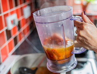  Chef filling up a plastic jug with steaming chopped carrot, ginger, red onion, garlic and stock ready for blitzing in to a healthy and nutritious homemade soup in the blender