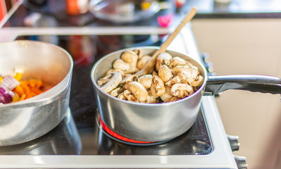 Organic mushrooms cooking on the hob in a stainless-steel saucepan - a stage required in making a healthy and nutritious mushroom and pasta dinner