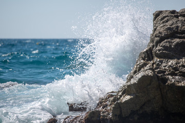 sea wave splashes over stone