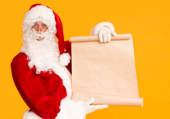 Santa showing big sheet of paper with copy space for wishes