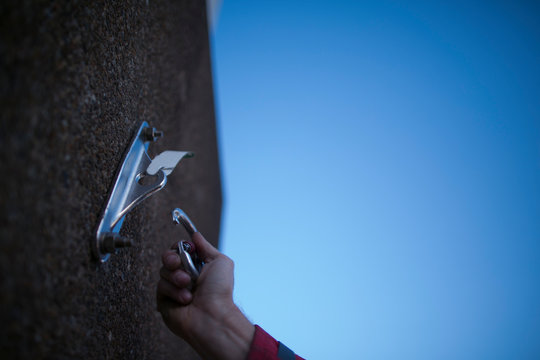 Worker clipping locking carabiner into industrial rope access fall arrest, abseiling stainless approved certified anchor point installed with expansion bolts on construction site, Sydney
