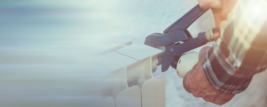 Repairman working on radiator with wrench; panoramic banner
