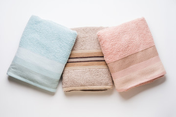 Pastel color clean folded towels on white background. Flat lay