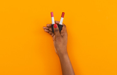 Matte red and pink lipsticks in black female hand