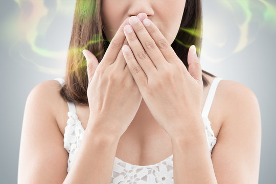Asian woman in white wear close her mouth against gray background, Bad breath