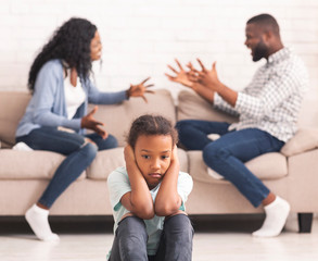 Upset black girl closing ears for not listening parents arguing