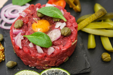Steak tartare of raw minced meat with salt and spices, on a black stone