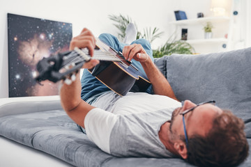 Man playing acoustic guitar in the living room.