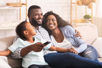 Happy afro family watching tv, relaxing together at home