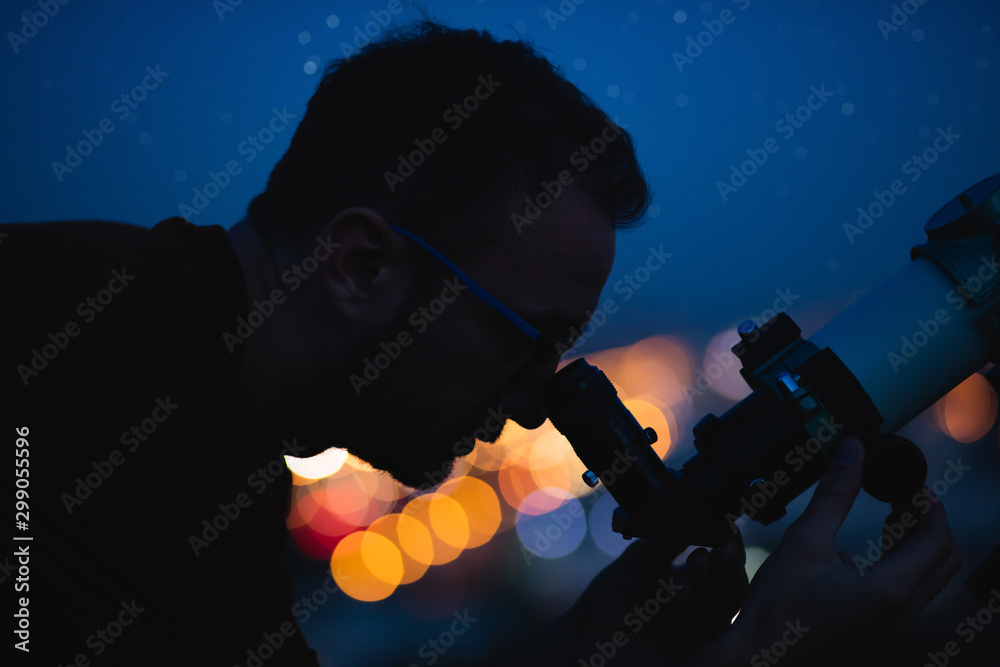 Canvas Prints astronomer with a telescope watching at the stars and moon with blurred city lights in the backgroun