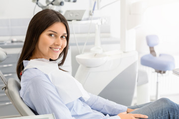 Brunette female patient sitting on dentist chair and smiling