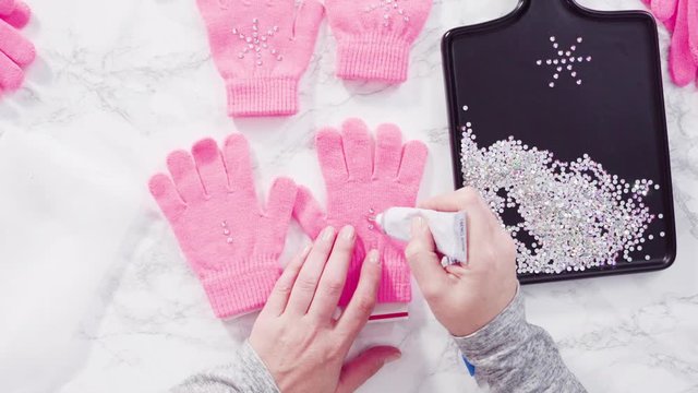 Flat lay. Rhinestone pink kids gloves with snowflake shapes.