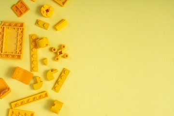 Obraz premium Yellow plastic cubes of the children's designer on a yellow background. Free space for an inscription.