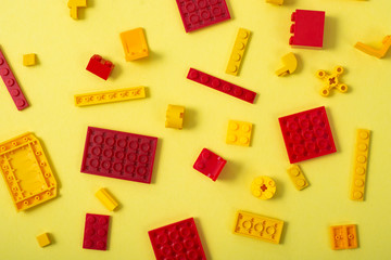 Yellow and red plastic blocks of the children's designer on a yellow background.