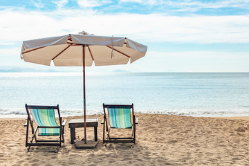 Beautiful panoramic view of Jabaquara beach in Ilhabela with chairs and umbrella on tropical island on the Brazilian sea coast during a sunny day of vacation and sightseeing trip.