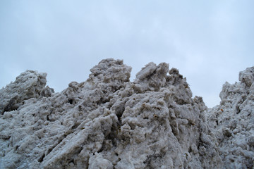 View from below on a dirty snowdrift against a cloudy sky.